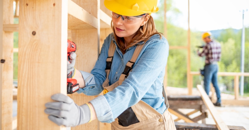 Female Construction Working Using a Drill
