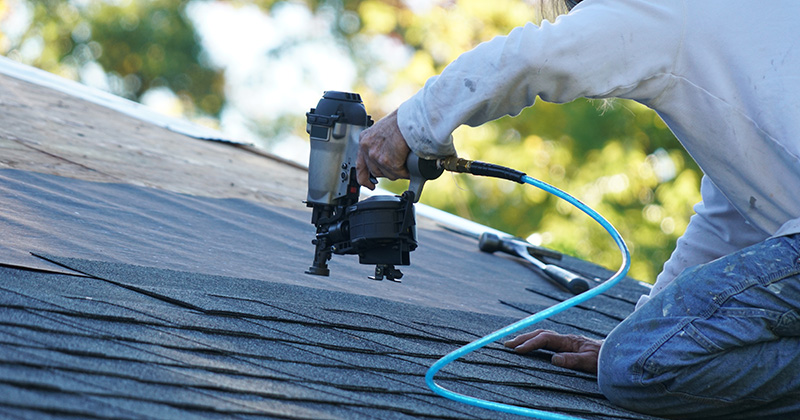 Roofer Nailing Down Shingles