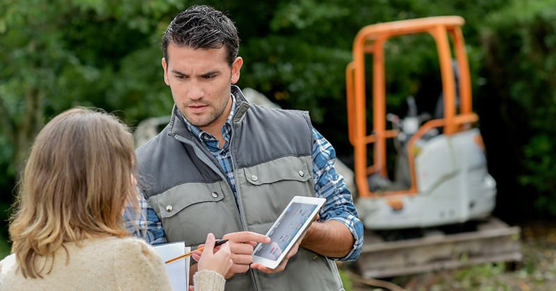 Male landscaper showing female customer information on tablet