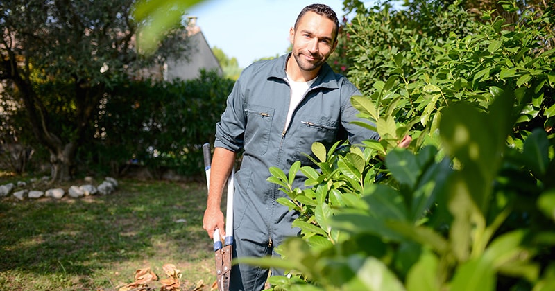  Male landscaper smiling at the camera and holding trimmers