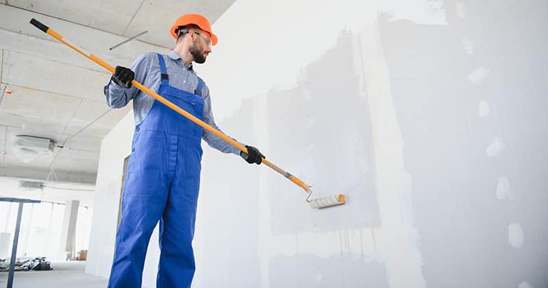 Commercial painter painting wall with paint roller