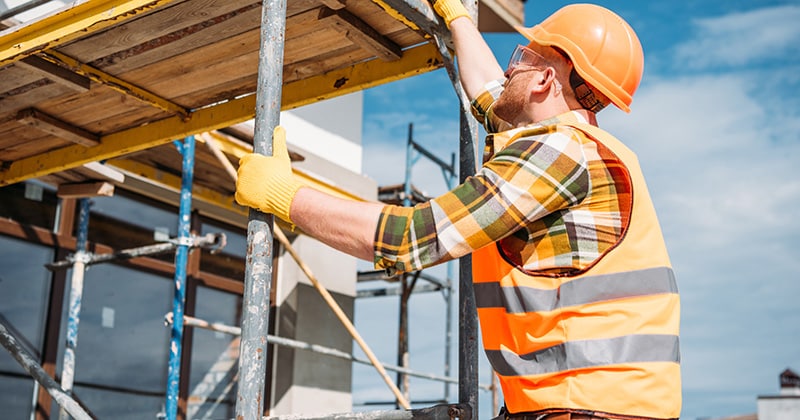 Construction worker climbing on scaffolding