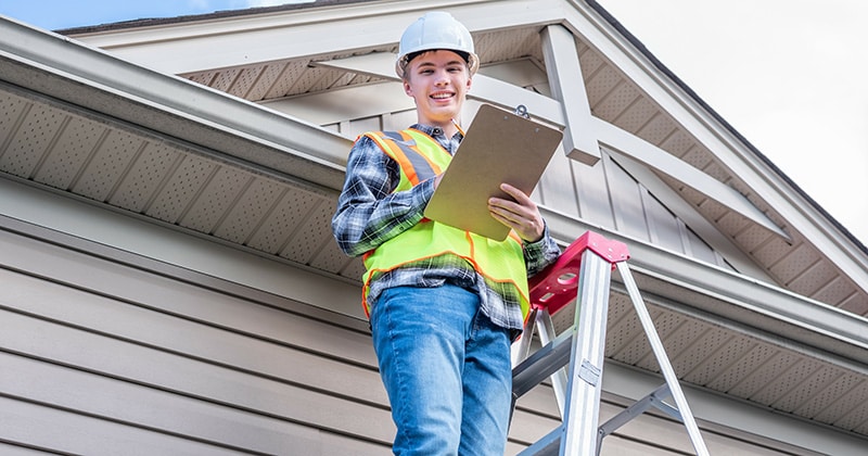 Inspector smiling with clipboard on ladder