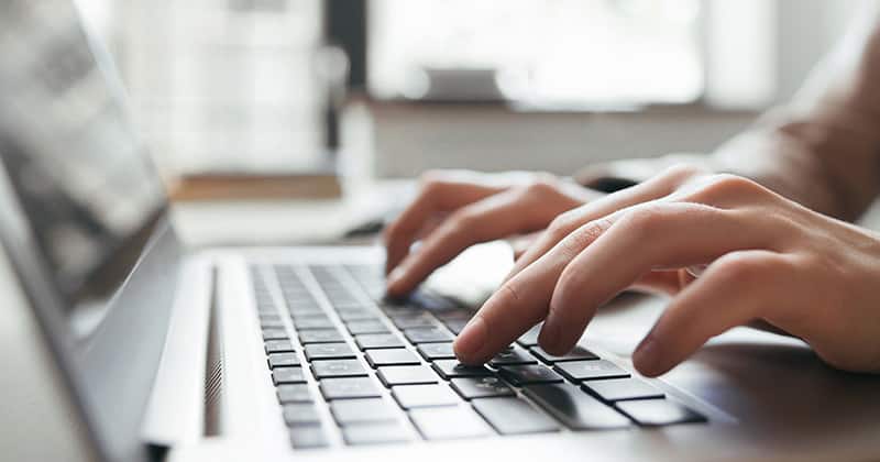 Person's hands typing on laptop