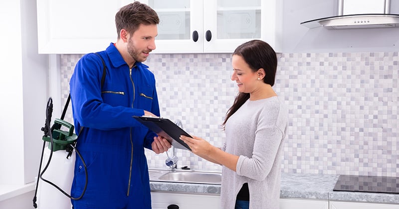 Pest control worker showing invoice to woman