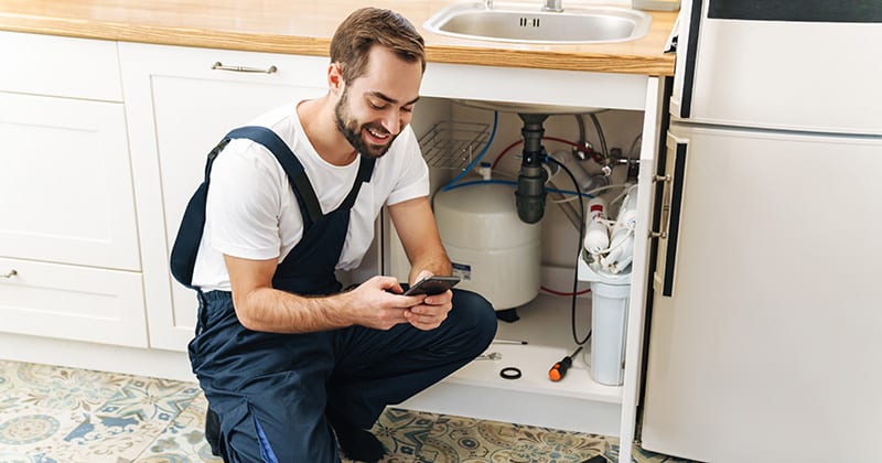 Plumber-on-the-job-using-his-mobile-phone