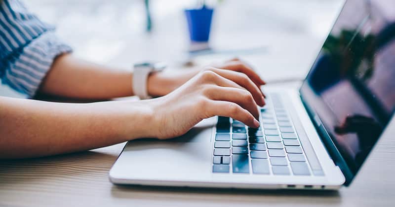 Hands typing on a laptop