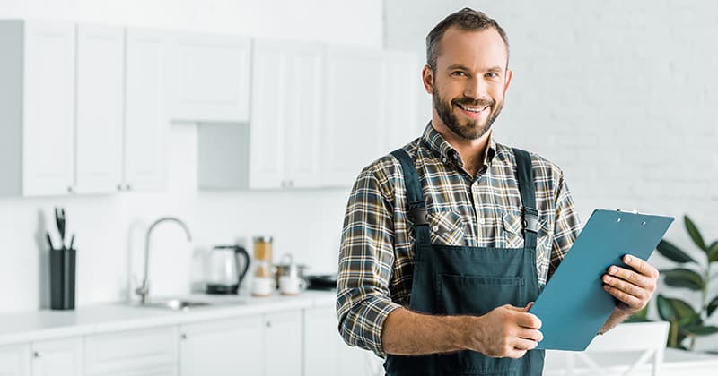 Plumber holding clip board and smiling