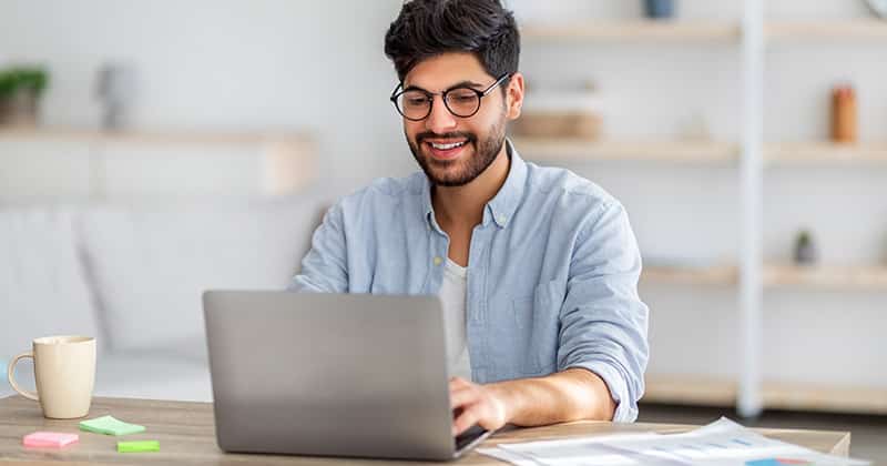 happy male typing on laptop