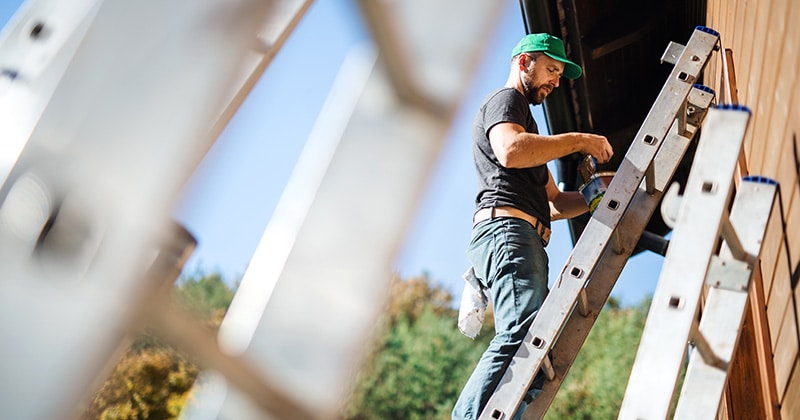 Man stands on ladder with paint can