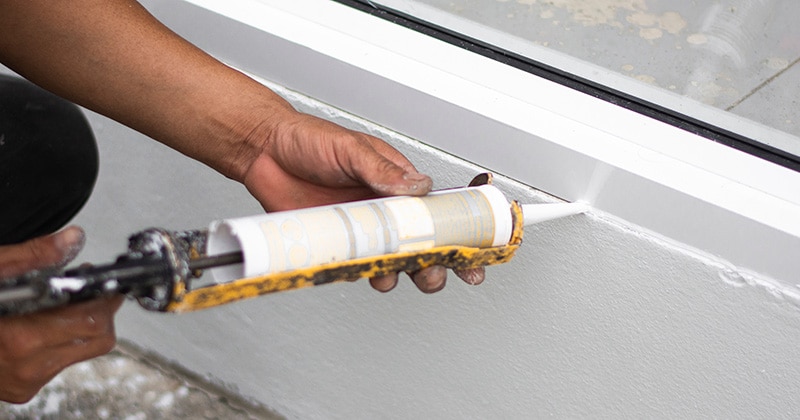 Repairman’s hand installing windows with caulking gun