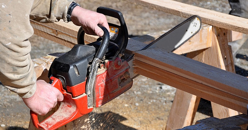 Cutting two-by-fours with chainsaw on jobsite