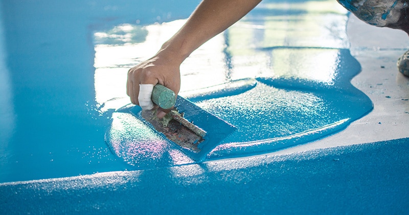 Field service tech leveling a blue epoxy floor