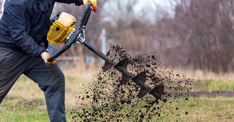 person holding earth auger