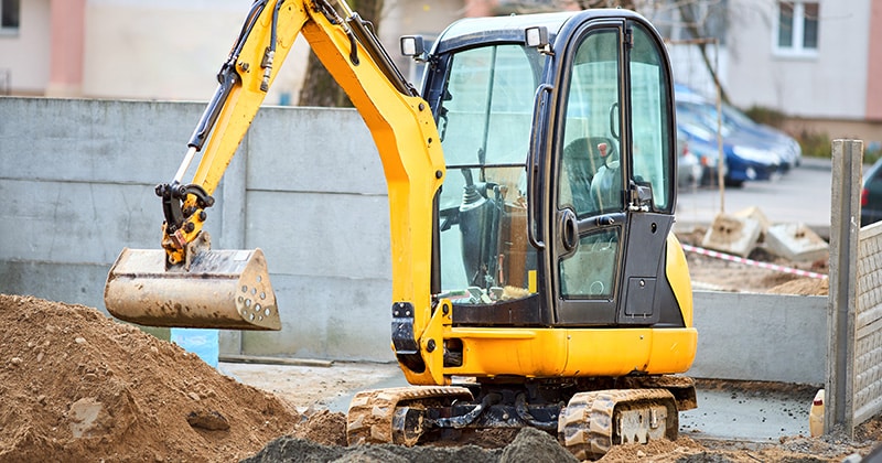 Mini excavator next to dirt pile