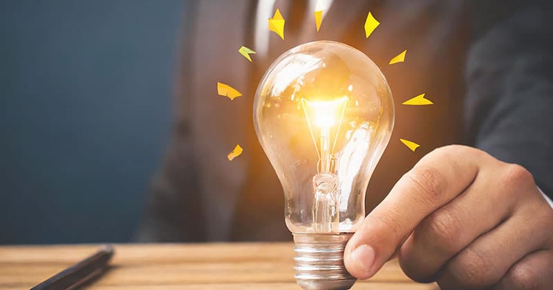 Hand holding lightbulb on desk, ideas and tips
