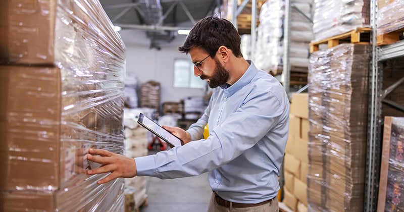 Man touching box and using ipad to Choose an Inventory Management System