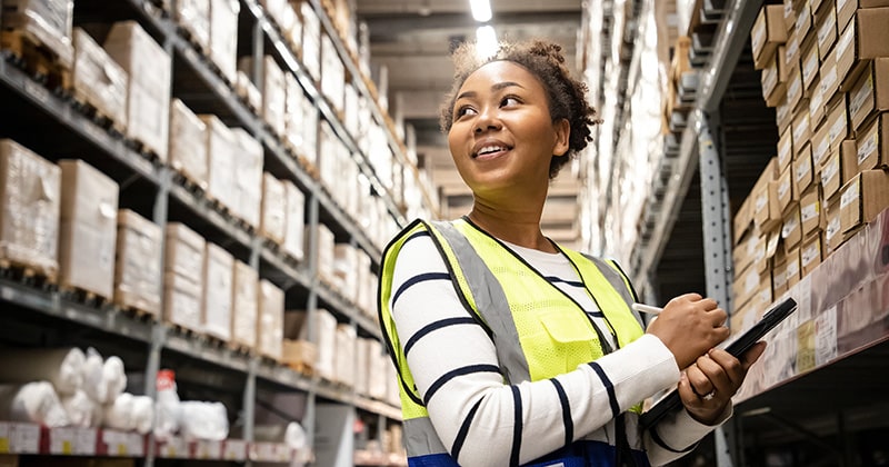 WOMAN IN WAREHOUSE CHOOSING INVENTORY MANAGEMENT SYSTEM