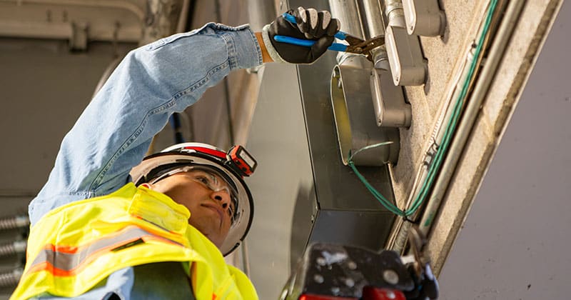Construction worker on ladder doing electrical work