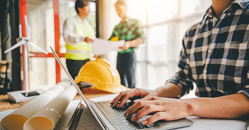 Construction team talking and planning on laptop