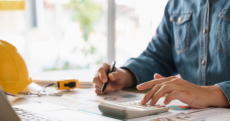 Construction manager at desk doing budget calculations