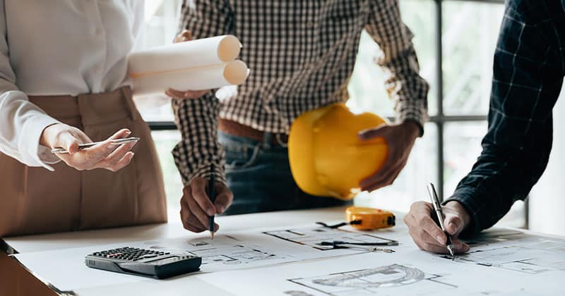 Construction team working at desk over blueprint